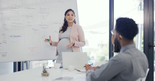Pregnant woman giving a presentation in a boardroom | Workplace Law Partners